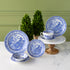 Burleigh Blue Willow Dinnerware displayed on a marble table with topiary plants behind it.