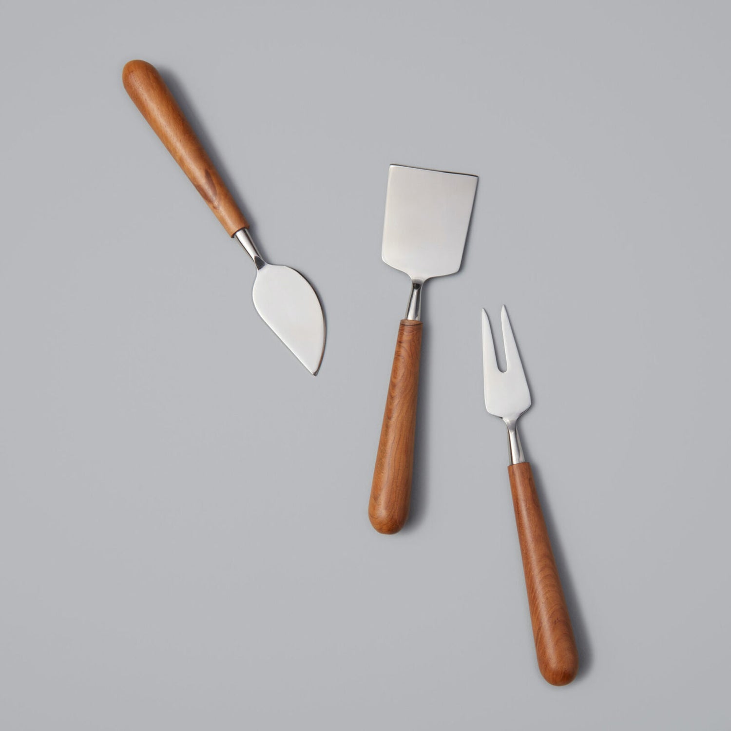 Teak &amp; Stainless Cheese Set by Be Home on a gray background.