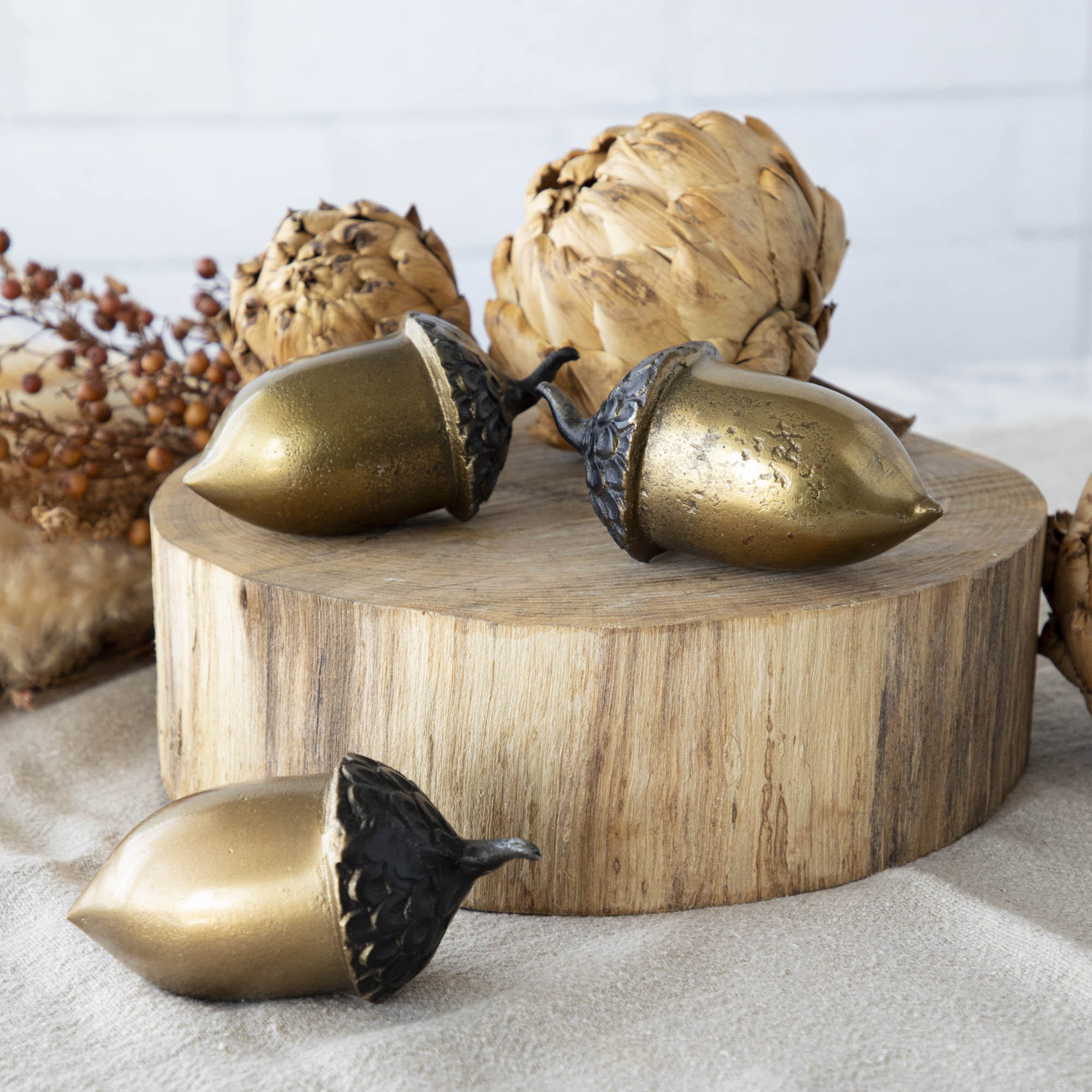 A set of three artificial brass acorns with an antique gold finish on a wooden surface.