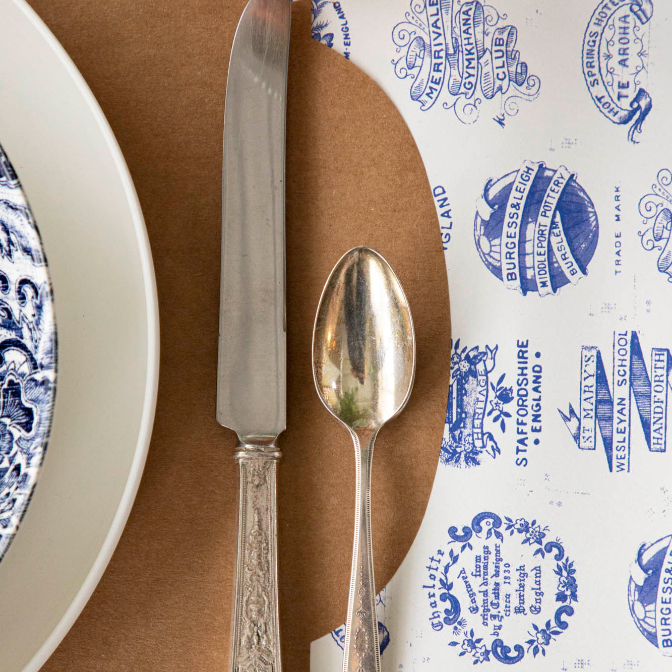 Burleigh Heritage Runner under the Kraft French Frame Placemat with an elegant place setting on top.