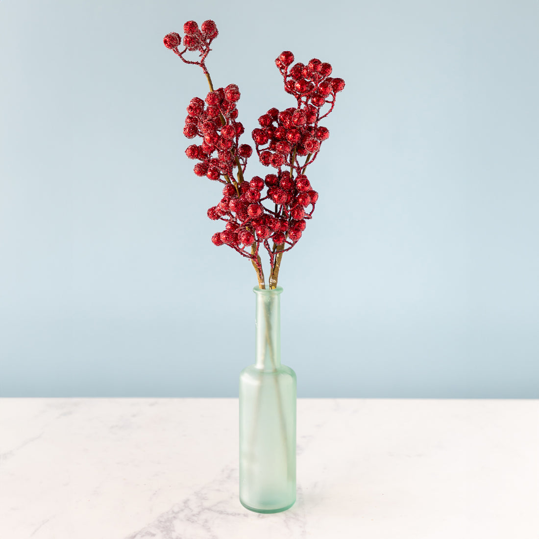 Cranberry Red Iced Picks in a green bottle, against a light blue background.