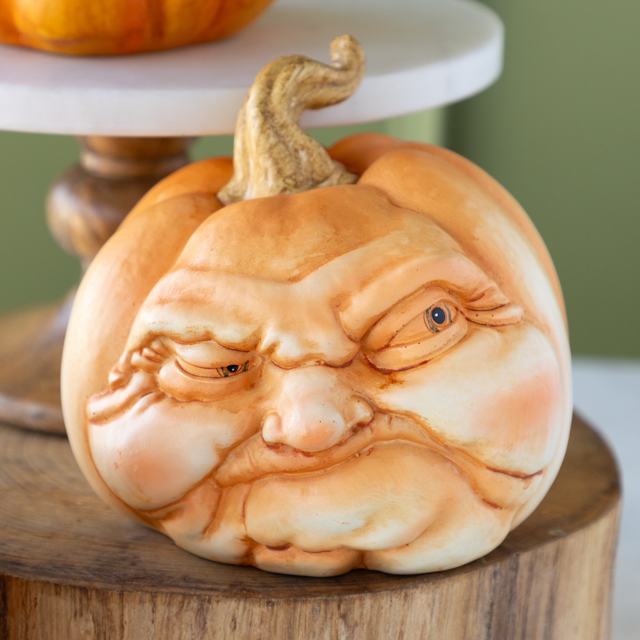 Decorative pumpkin with a scowling face on a wooden surface
