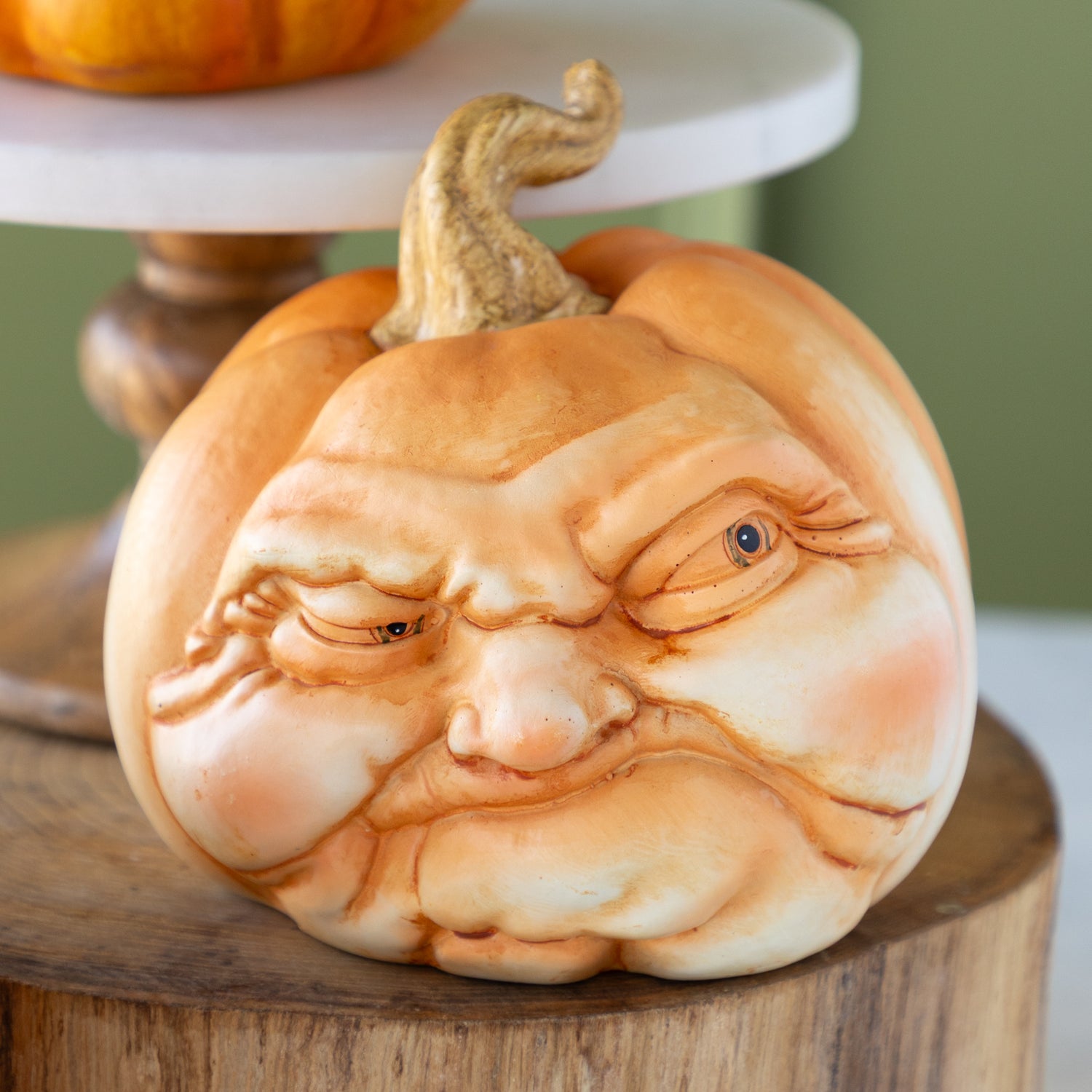 Decorative pumpkin with a scowling face on a wooden surface