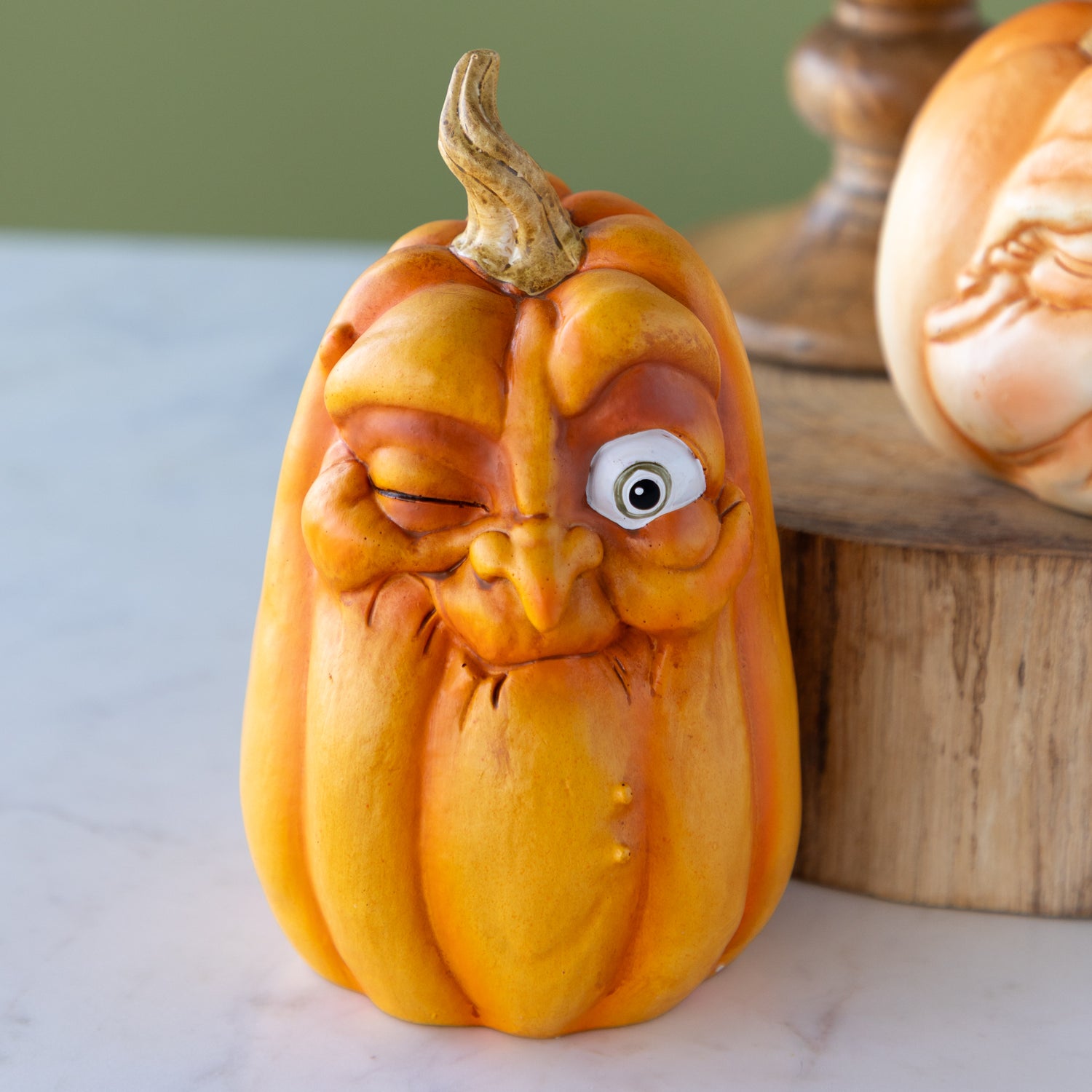 Decorative pumpkin with a winking face on a neutral background.