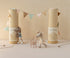 Two stuffed animal toys with decorative boxes and a string of flags on a neutral background. 