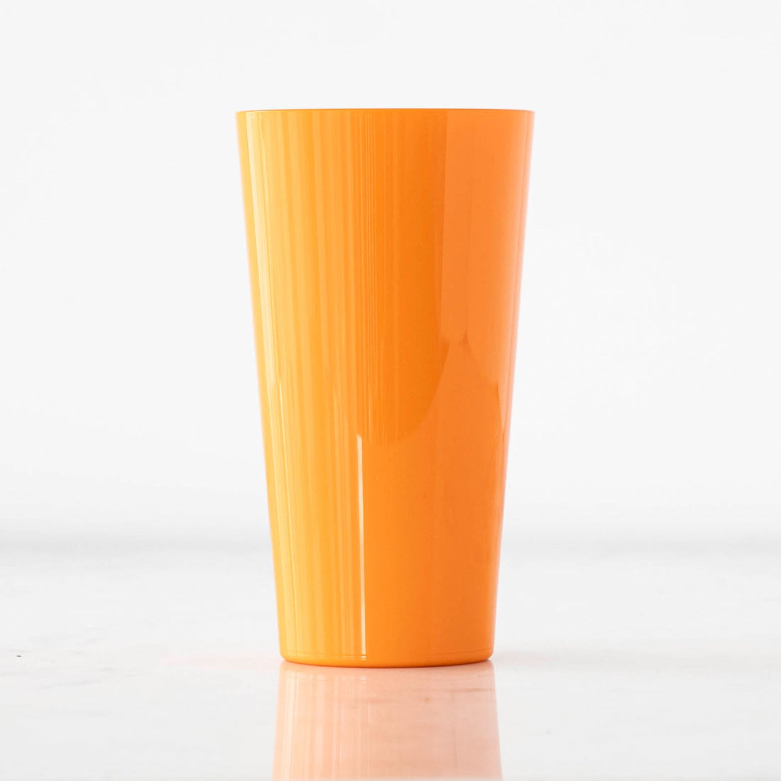 A bright orange cup made from shatterproof material, crafted to look like glass.