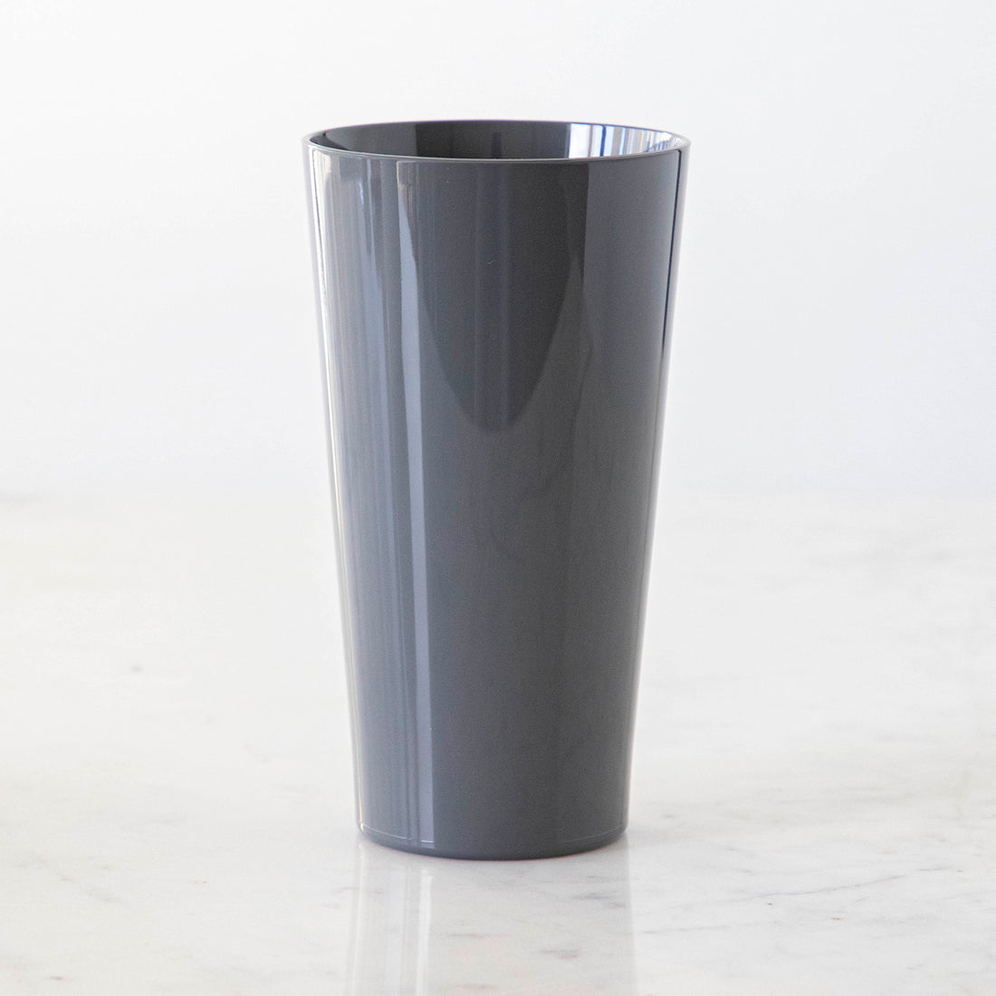 A Gray Pint symGlass on a marble table.