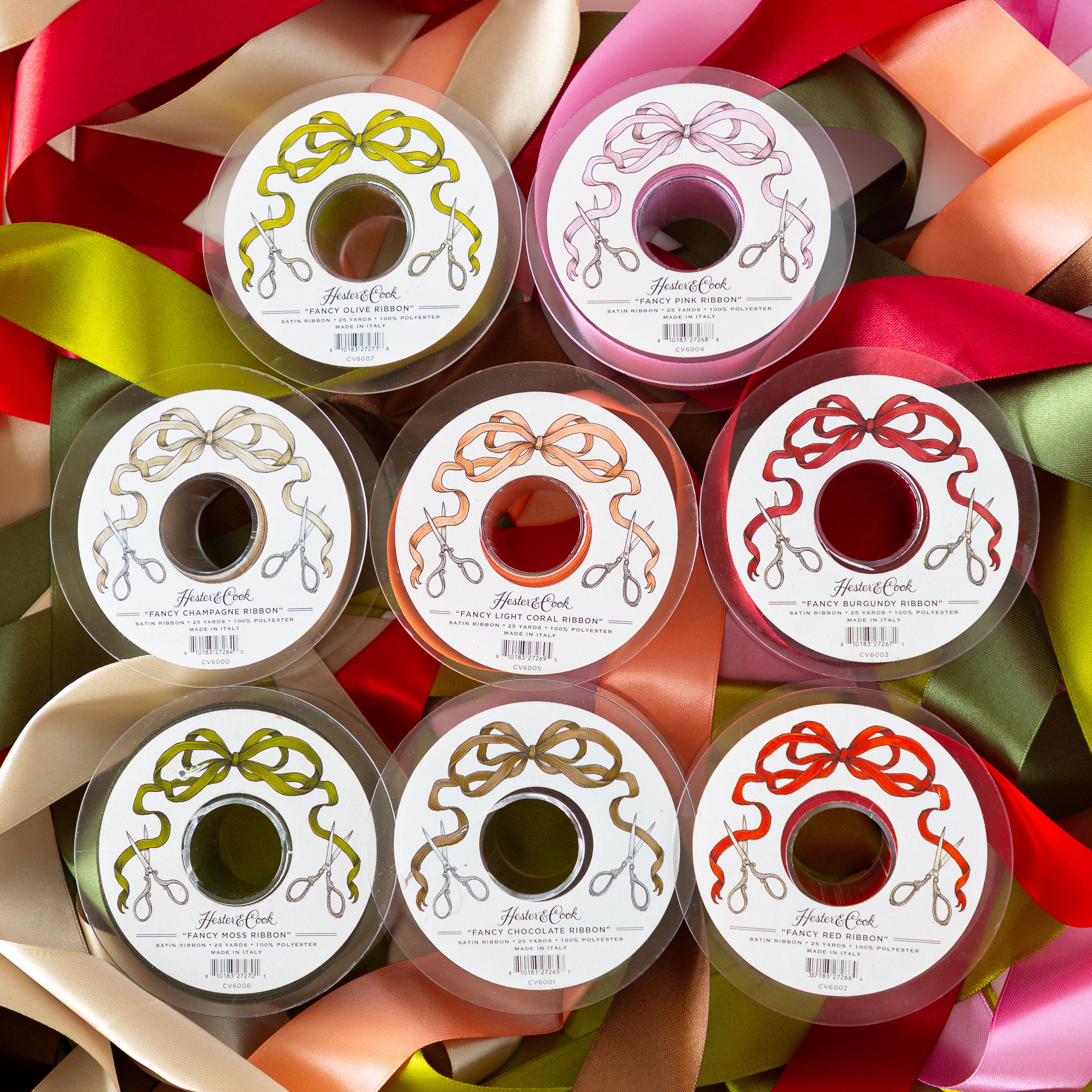 Assorted spools of Hester & Cook Fancy Ribbon with decorative labels on top of colorful ribbons.