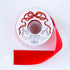 A spool of red satin ribbon with a label featuring illustrated scissors and red bow branded "Hester & Cook Fancy Red Ribbon.
