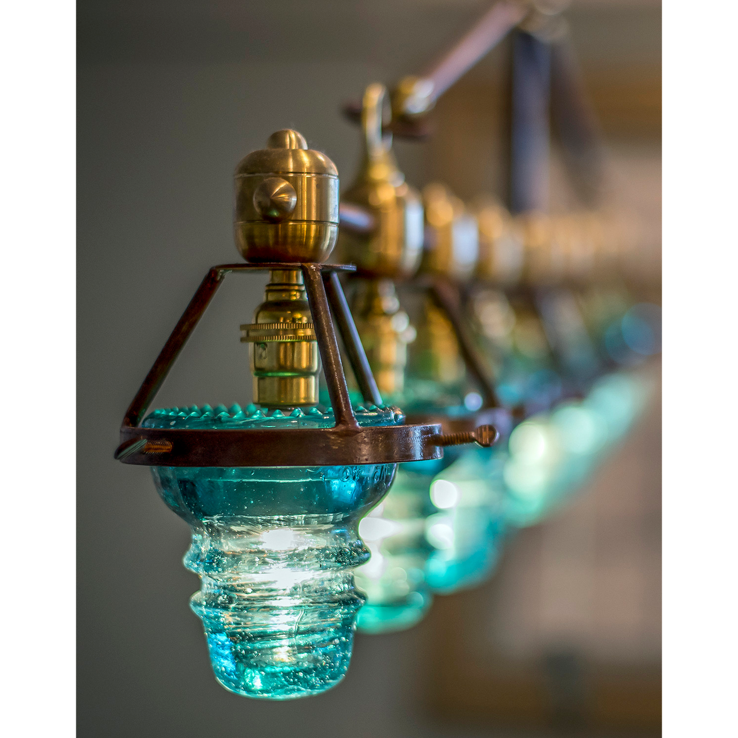 A Telegraph Pendant Lighting with four glass shades and antique insulators hanging from a brass frame. (Brand Name: Hester & Cook)