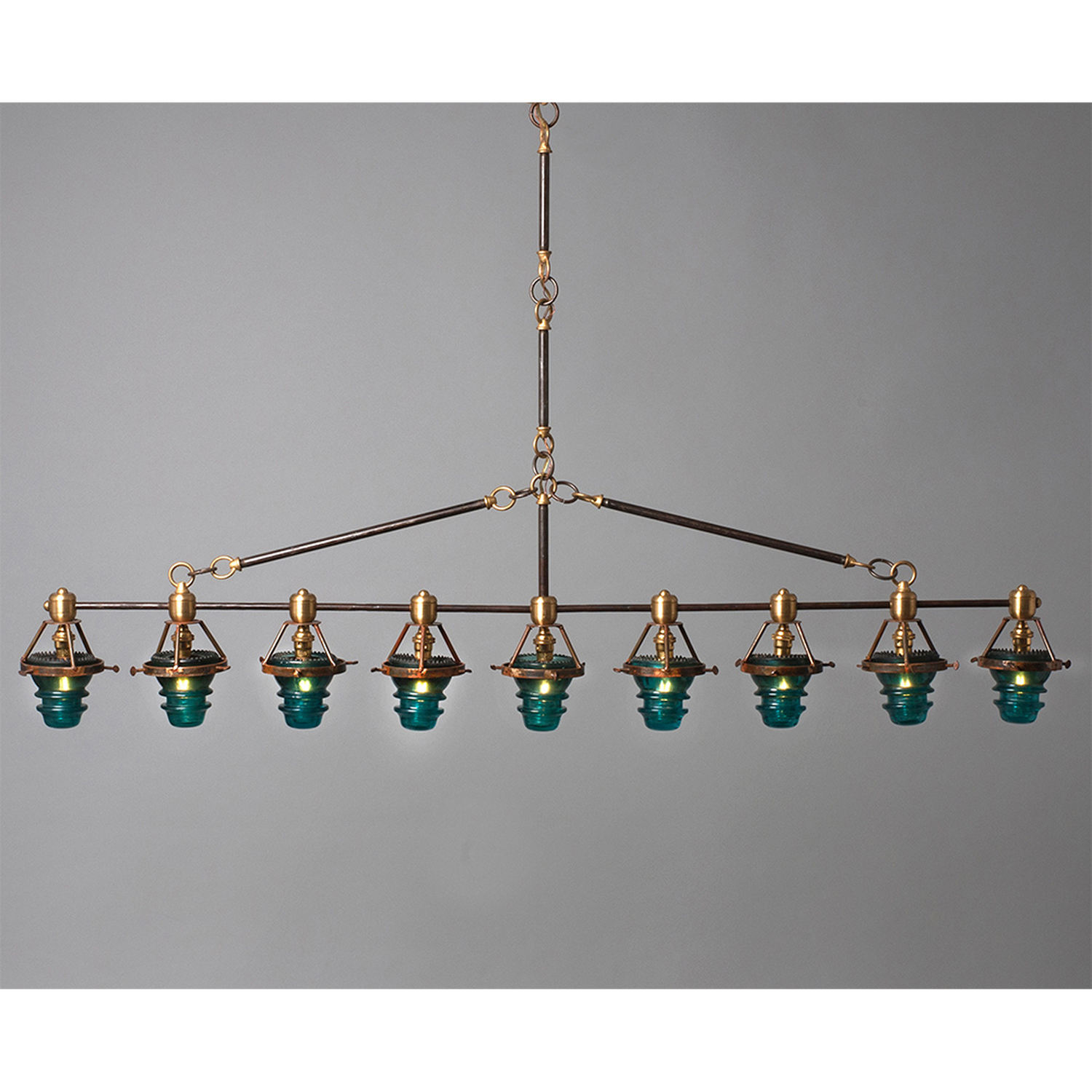 A Telegraph Pendant Lighting with four glass shades and antique insulators hanging from a brass frame. (Brand Name: Hester & Cook)