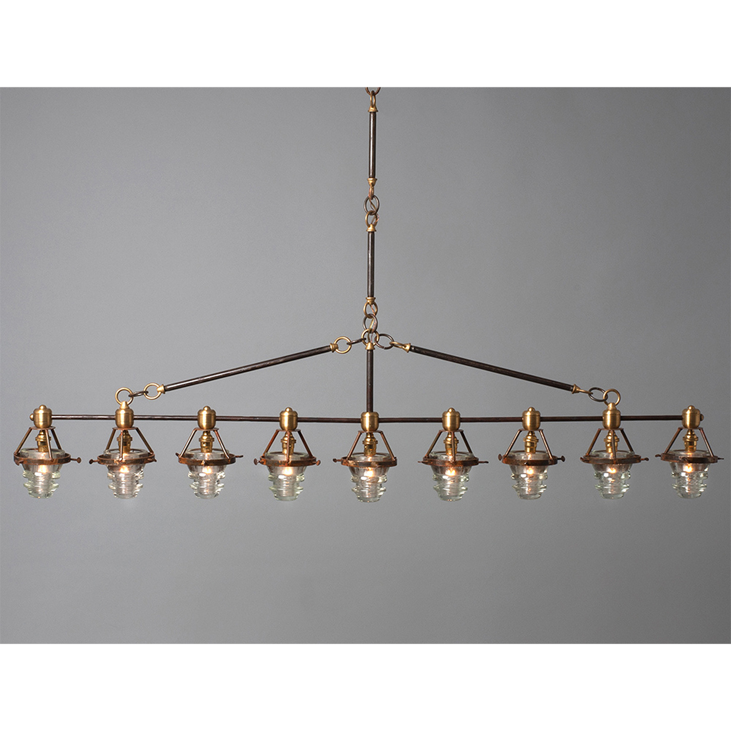 A Telegraph Pendant Lighting with four glass shades and antique insulators hanging from a brass frame. (Brand Name: Hester & Cook)