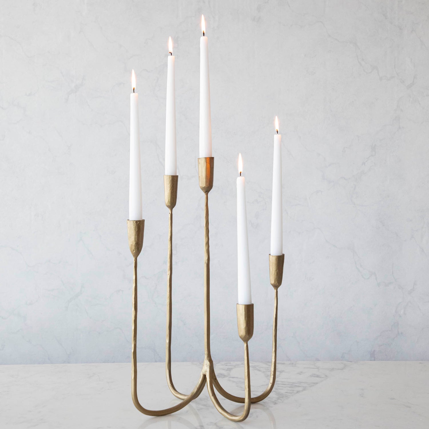 Tall Brass Forged Candelabra with white candles burning in it. 