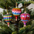 A set of three glass hot air balloon ornaments in red, blue, and green stripes, hanging on a Christmas tree.