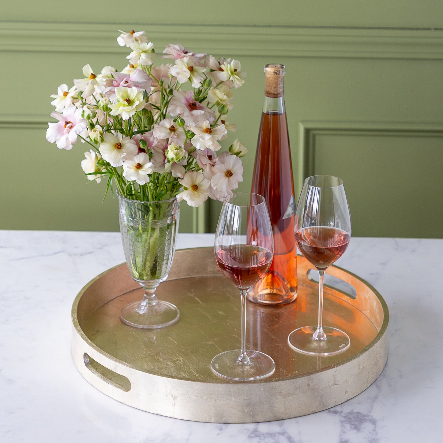 Champagne Silver Round Foiled Tray with two wine glasses, a bottle of wine and a vase of flowers in it.