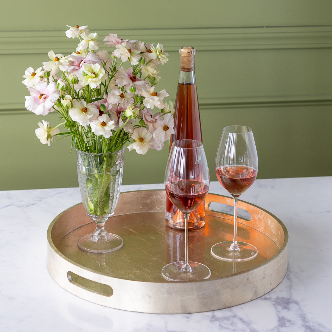 Champagne Silver Round Foiled Tray with two wine glasses, a bottle of wine and a vase of flowers in it.