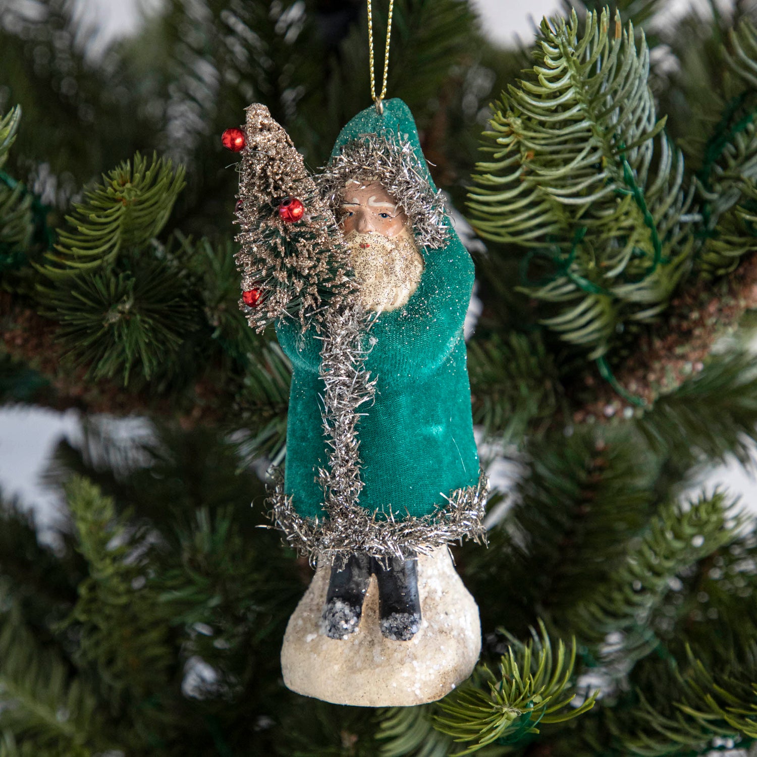 A teal-robed Santa Claus ornament on a tree.