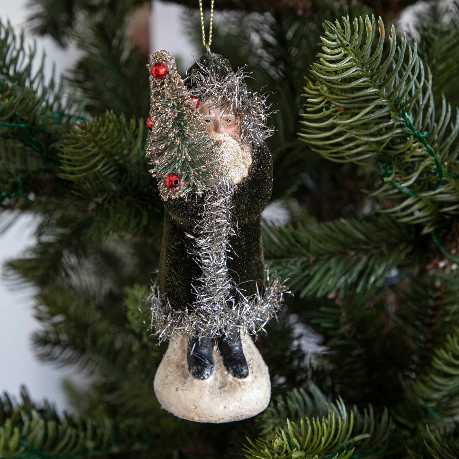 A moss green-robed Santa Claus ornament on a tree.