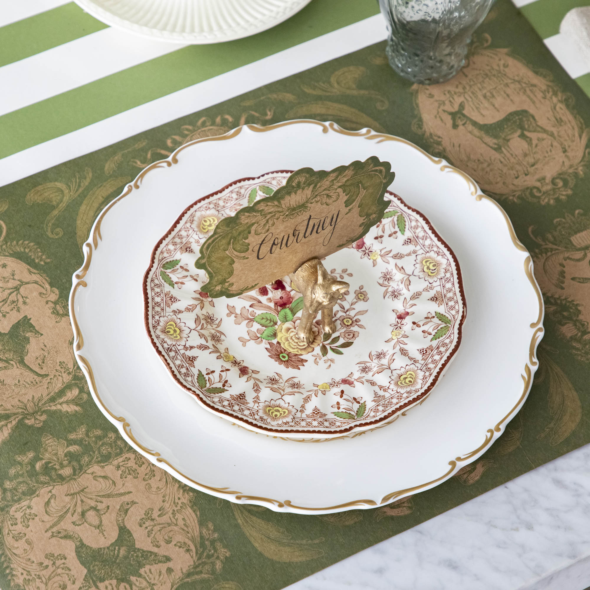 The Fox Name Card holder holding the Moss Fable Toile Place Card with "Courtney" written in cursive, held by a slot in the Fox&