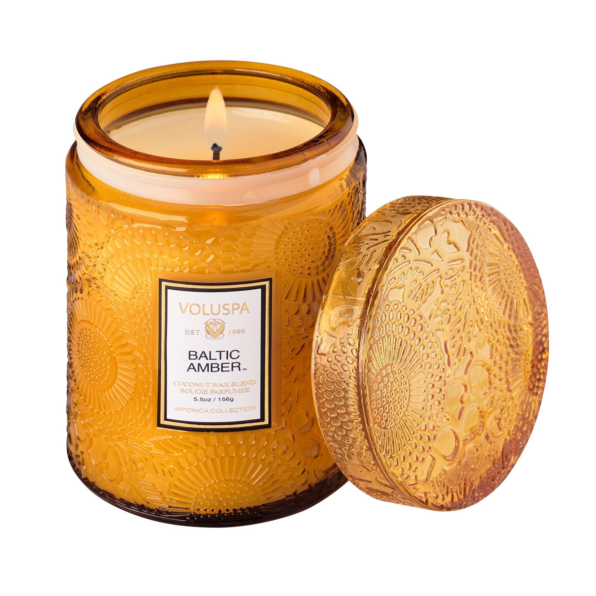 Two Voluspa Baltic Amber candles with matches on a marble surface.