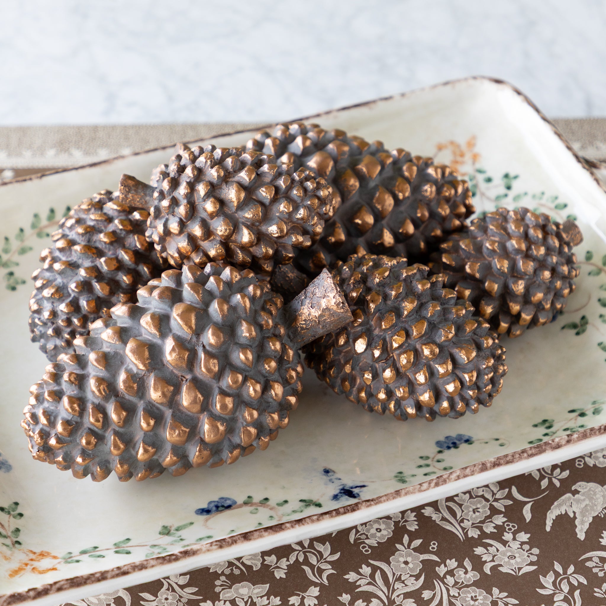 Decorative tray with bronze pinecones on the Brown Regal Peacock Runner.