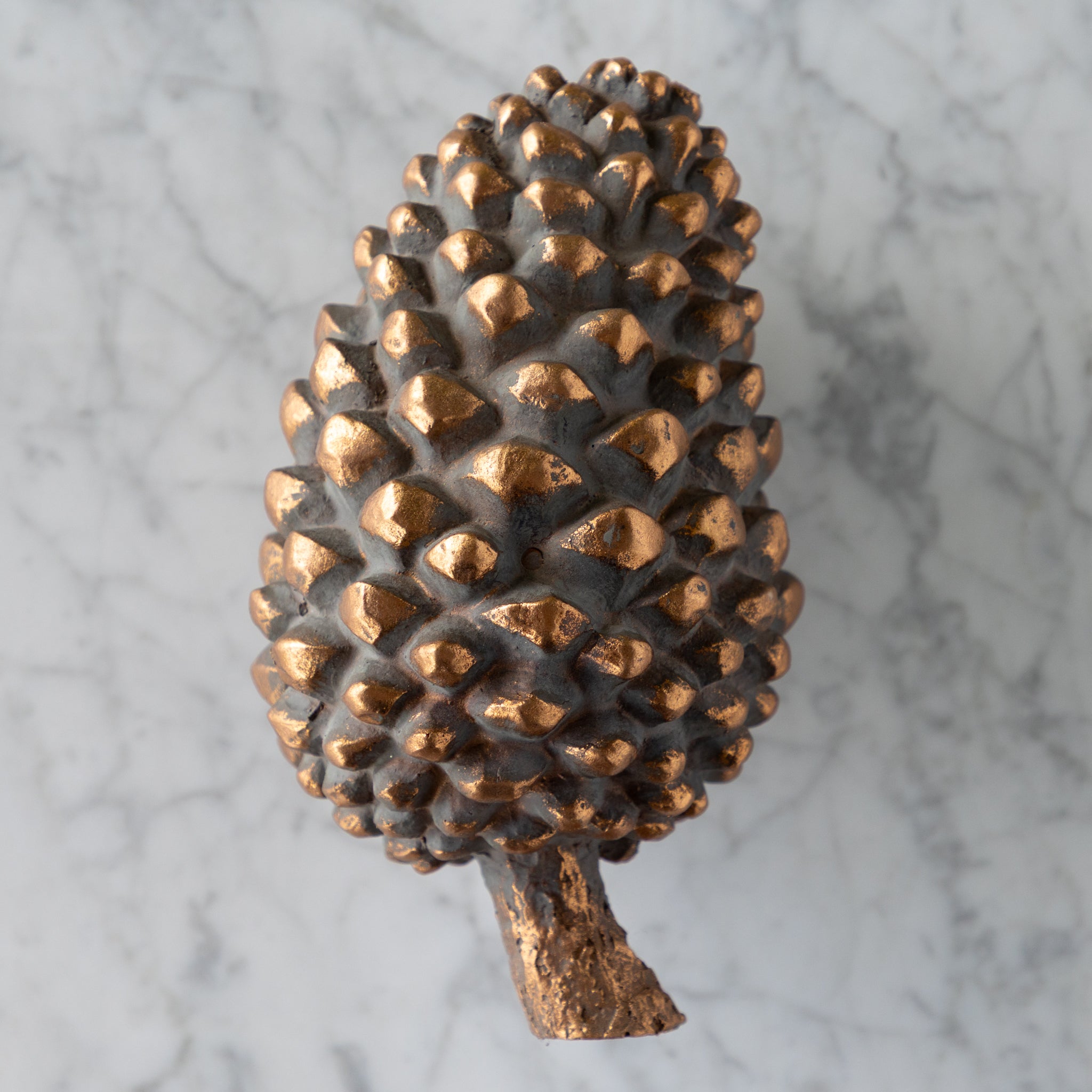 Bronze pine cone on a marble surface.