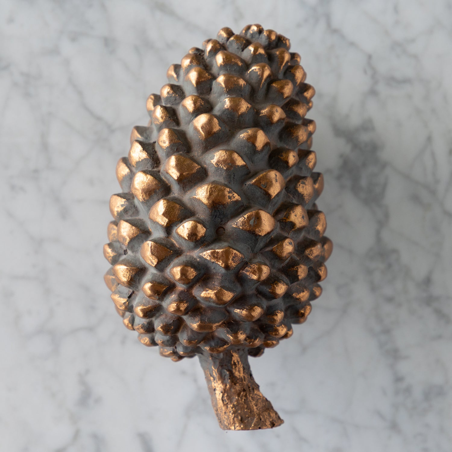 Bronze pine cone on a marble surface.