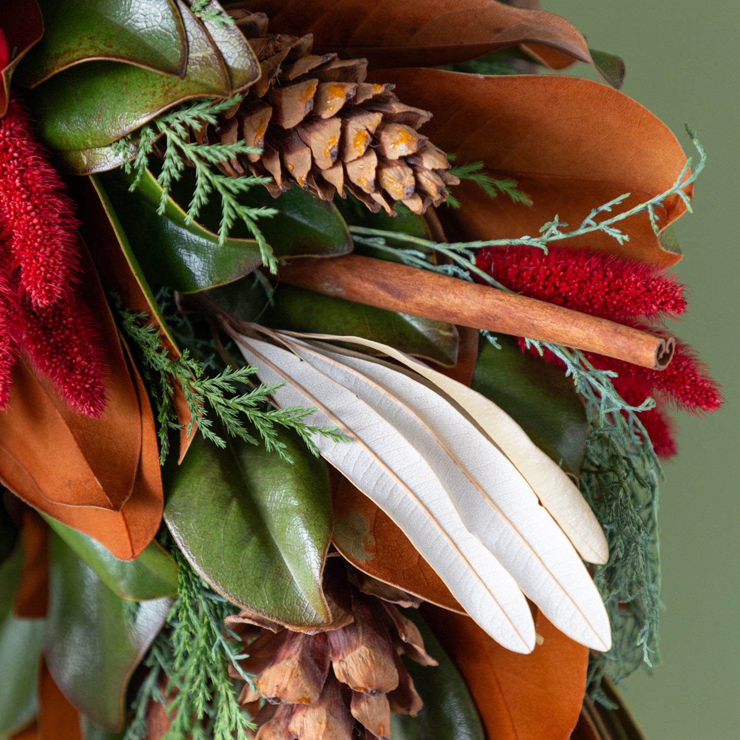 Close up of cinnamon stick and assorted greenery on wreath. 