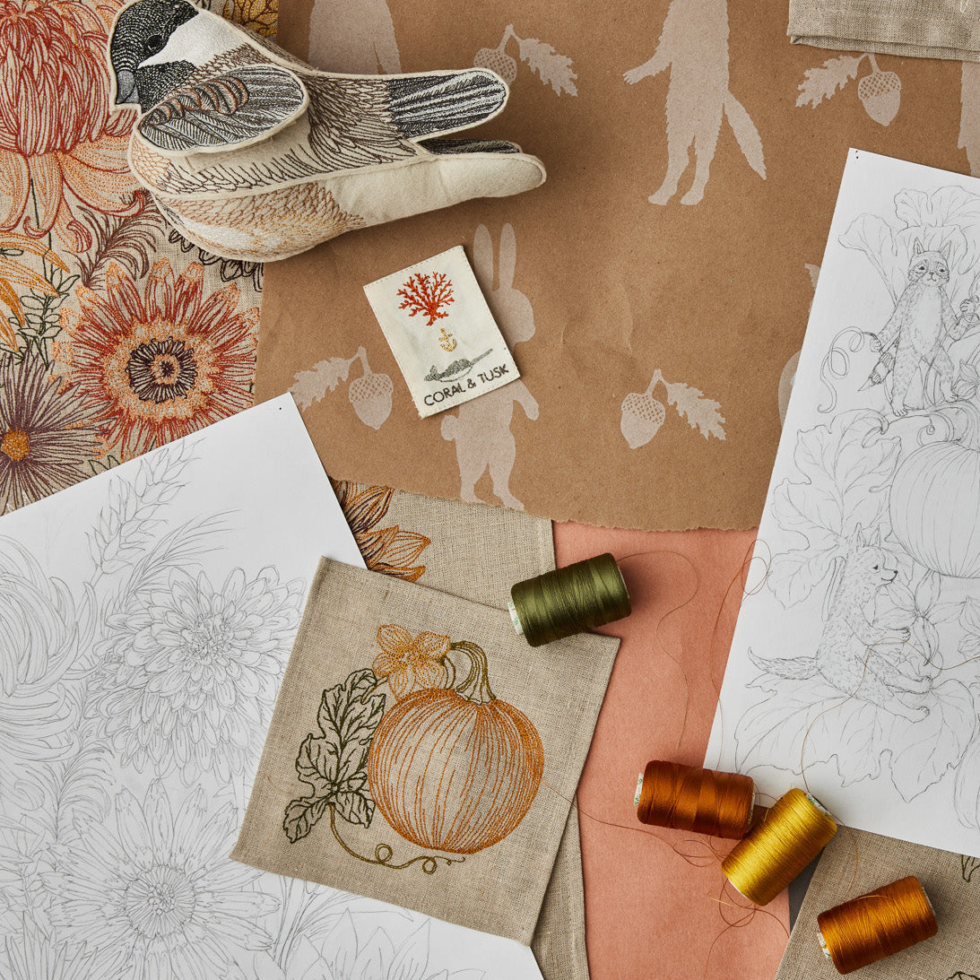 Collection of patterned paper, fabric swatches, and thread spools on a textured surface.