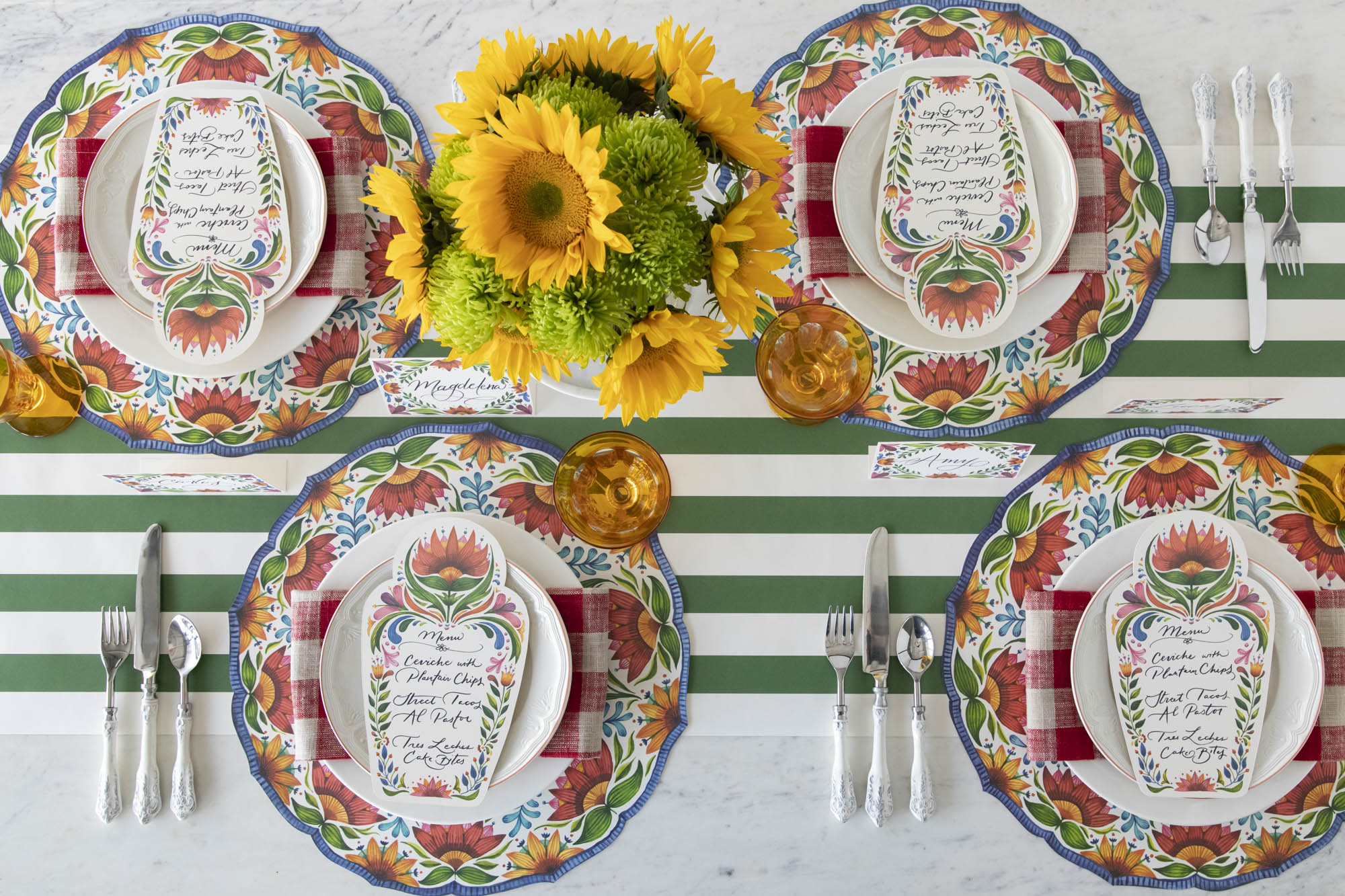 A colorful table setting for four with sunflowers, plates, and Die-cut Fiesta Floral Placemats from Hester & Cook, from above.