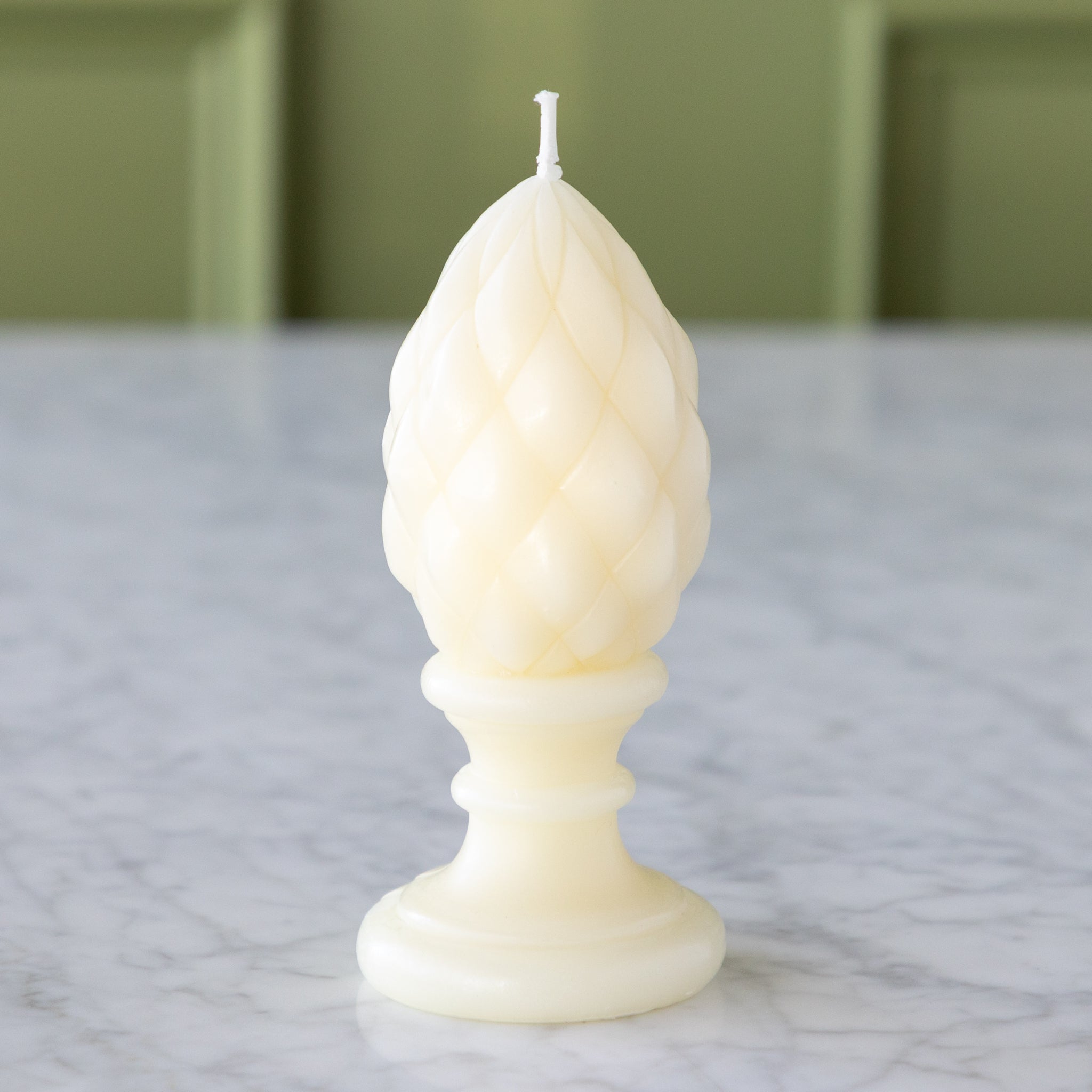 White candle with a decorative design on a marble surface.