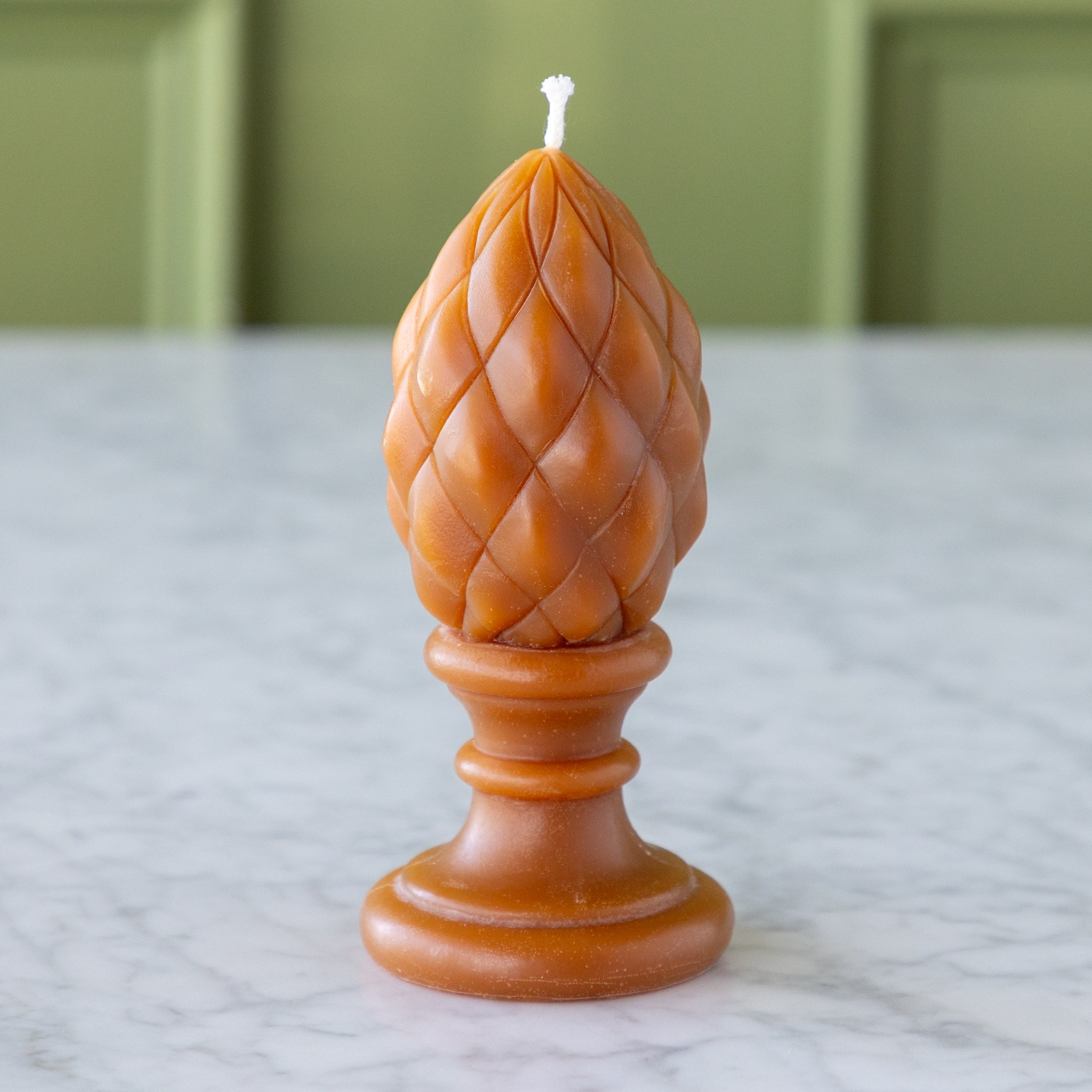 Decorative candle with a woven design on a marble surface.