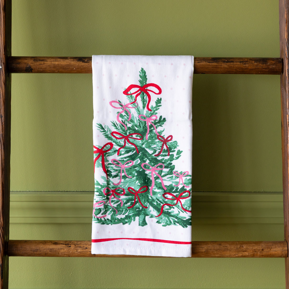 Very Merry Dishtowel hung on a wooden ladder.
