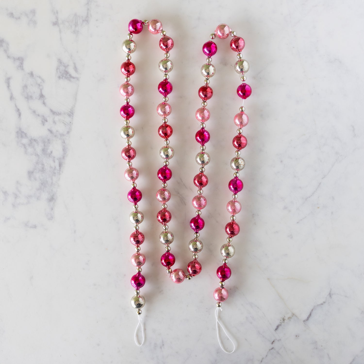 Pink &amp; Silver Vintage Ornament Garland on a marble table.
