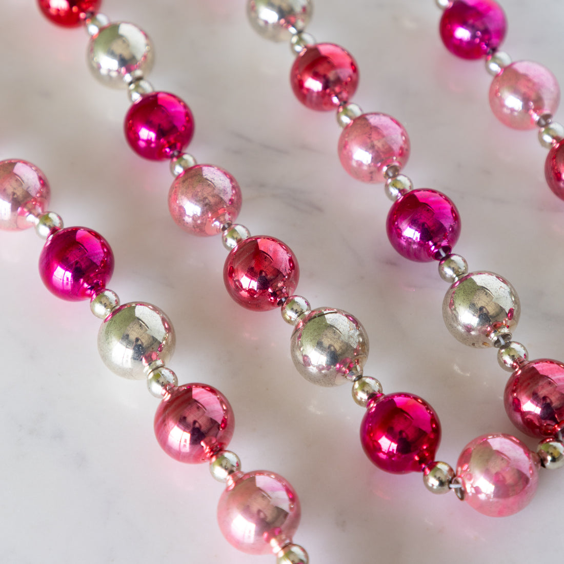 Pink &amp; Silver Vintage Ornament Garland on a marble table.