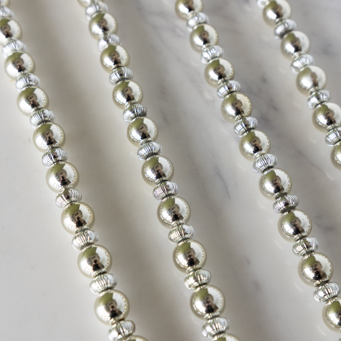 Close-up of Silver &amp; Gold Bead Garland  on a marble surface. 