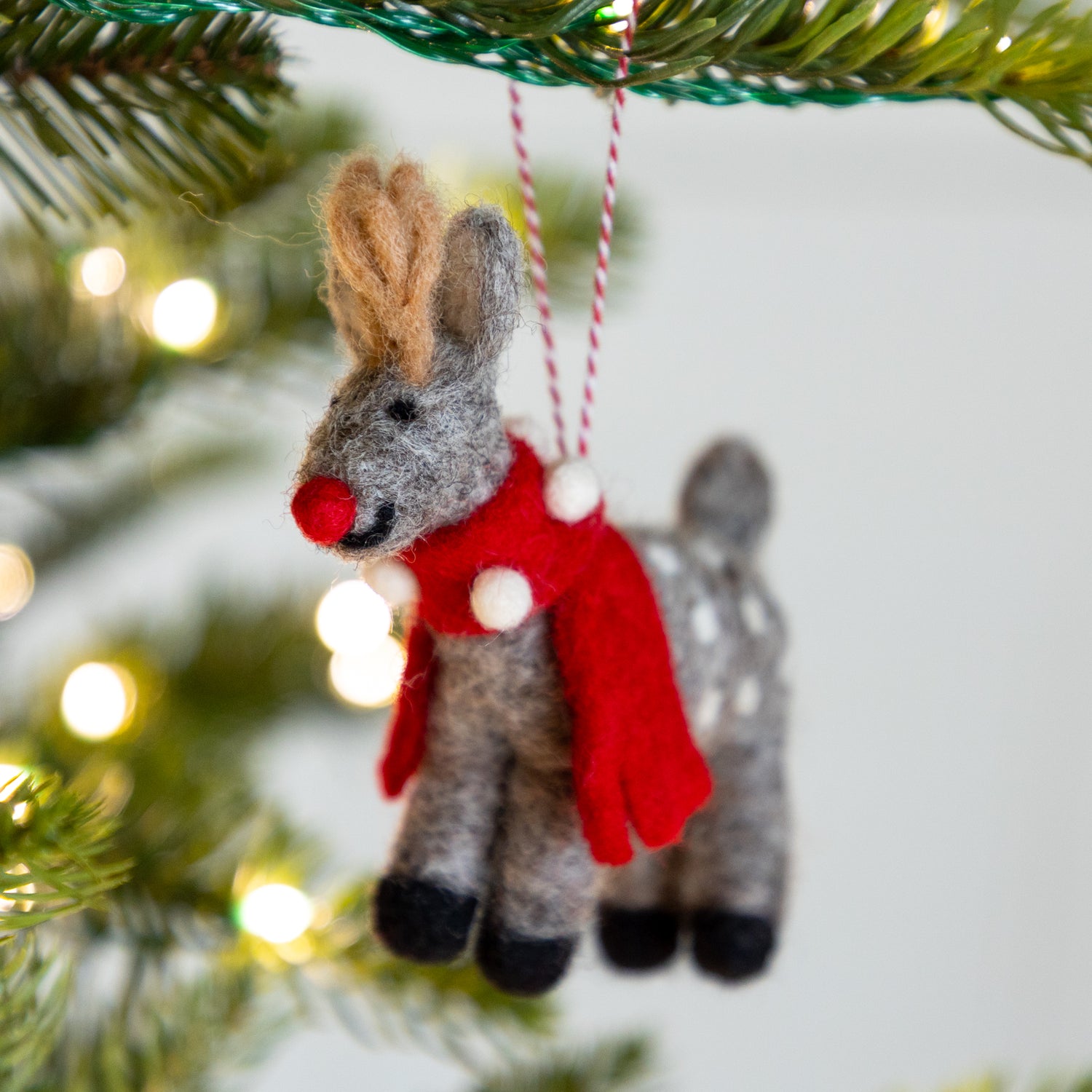 Felt Reindeer Ornament with a red scarf and red nose hanging on a Christmas tree.