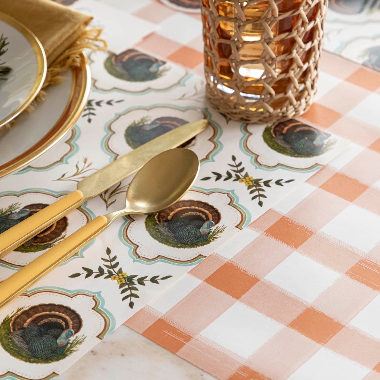 Heritage Turkey Meadow Placemat on an orange checked runner with dinnerware on top.