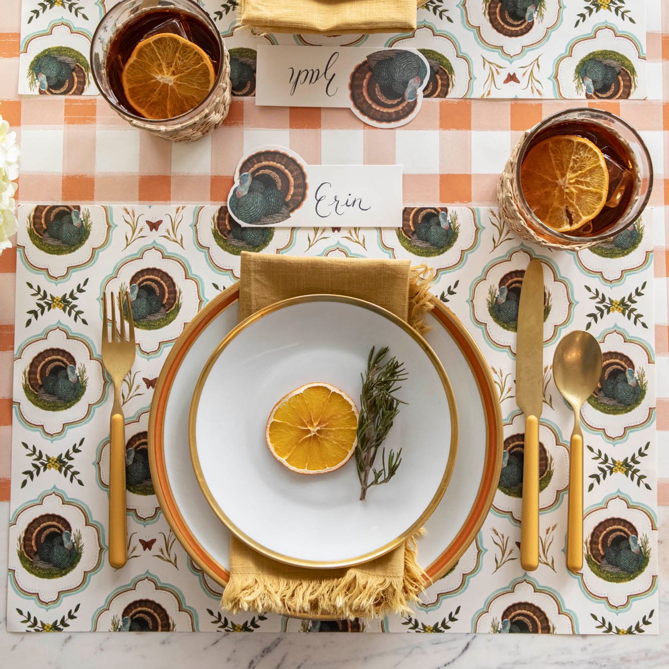 Elegant tablescape featuring the Heritage Turkey Meadow placemat with dinnerware, a napkin and orange garnish on top.