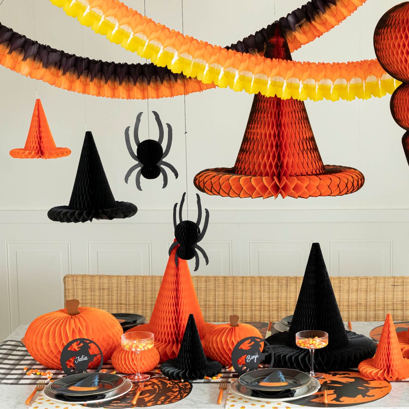 Hanging orange, black & yellow various honeycomb overtop of a Halloween themed table with more Halloween honeycomb.