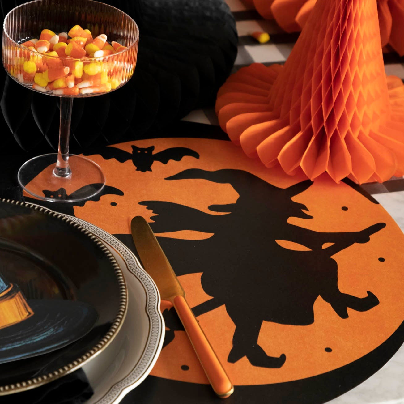 Die-cut Wicked Witch Placemat with a table setting, candy corn and halloween decor.