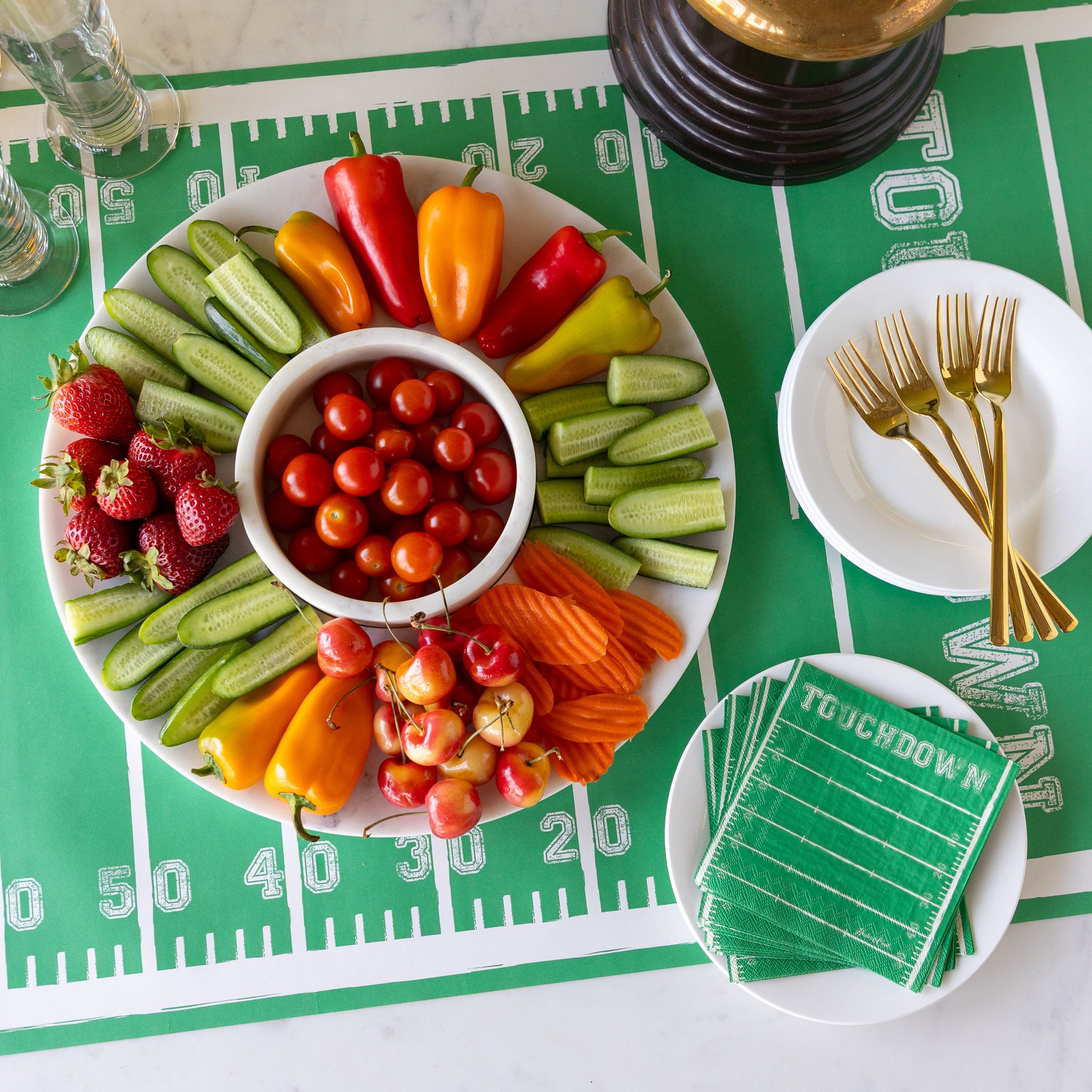 Marble Chip and Dip Server with fruits and veggies atop, Touchdown Cocktail Napkins, a gold trophy, and glasses, plates and forks on the Touchdown Runner.