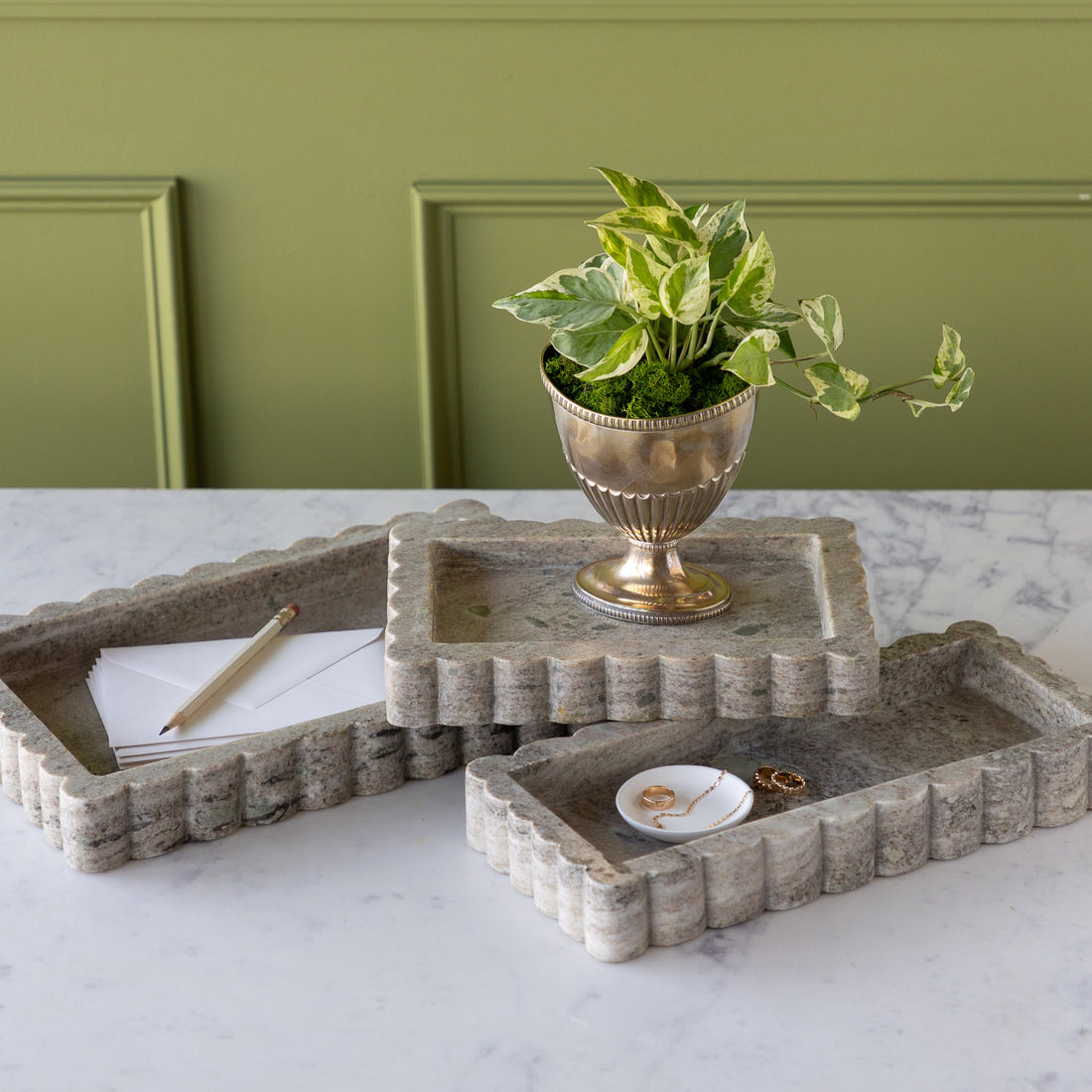 Intricate Scallop Marble Trays in 3 sizes with a potted plant in the small, trinket dish with jewelry in the medium and envelopes and a pencil in the large.