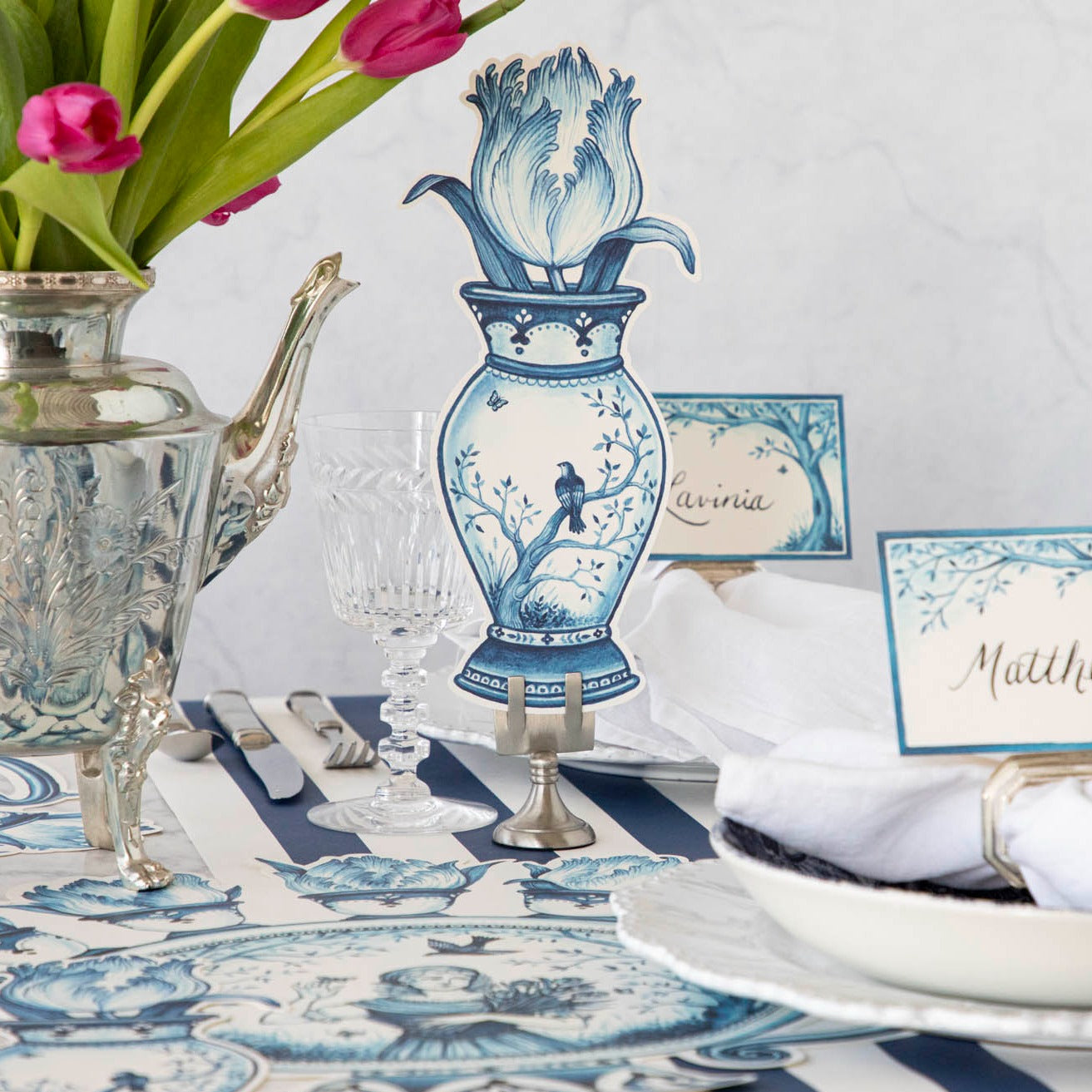 A versatile Indigo Tulip Table Accent featuring a blue and white table setting with a vase and tulips by Hester & Cook.