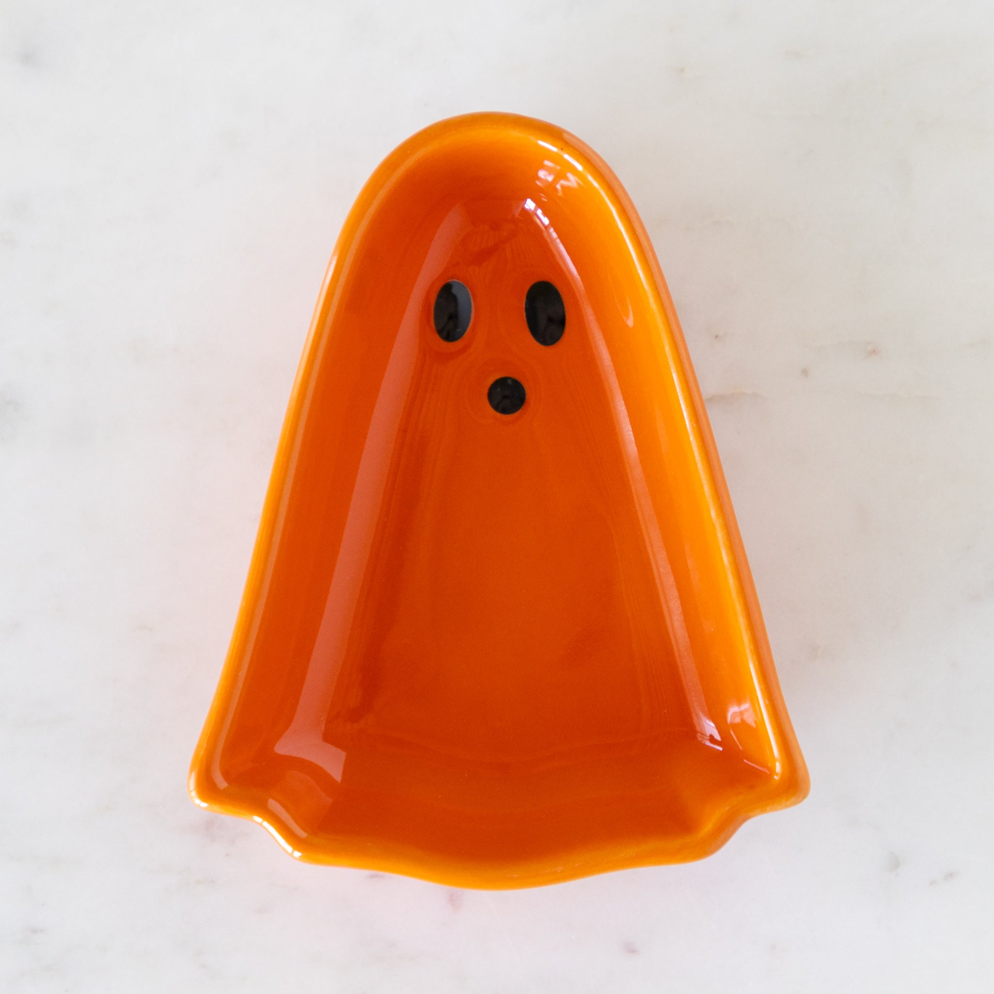 Ghost Pinch Bowl in orange on a marbled table.