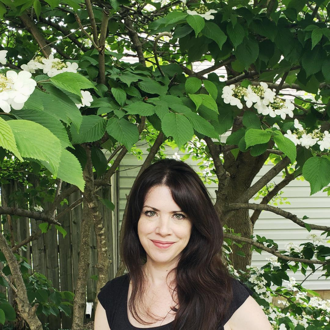 Artist, Janet Hill in front of a tree.