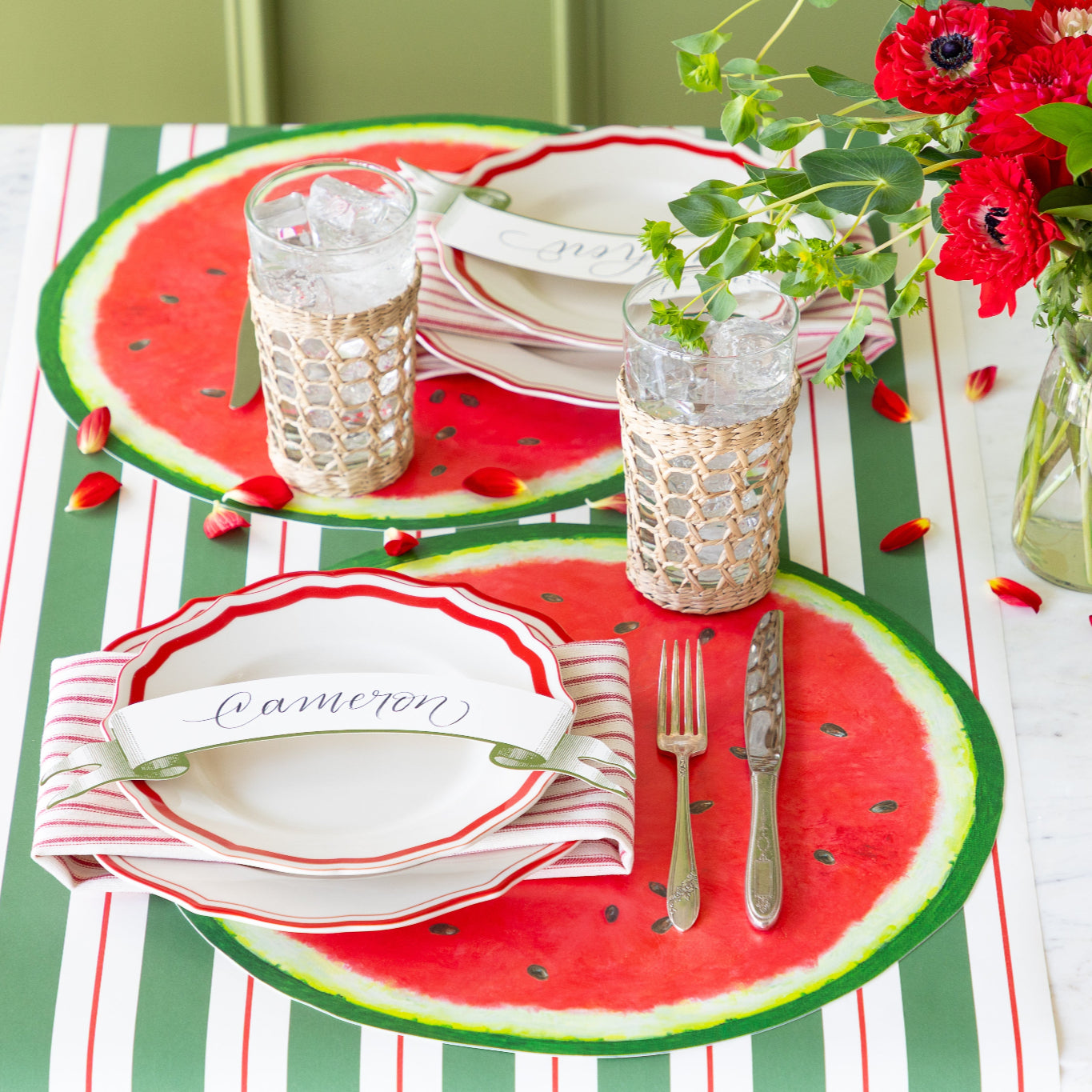 Place setting with the Die-cut Watermelon Placemat, Fancy Red Scalloped Plates, Classic Moss Banner Table Accent and silverware on the Green & Red Awning Stripe Runner.