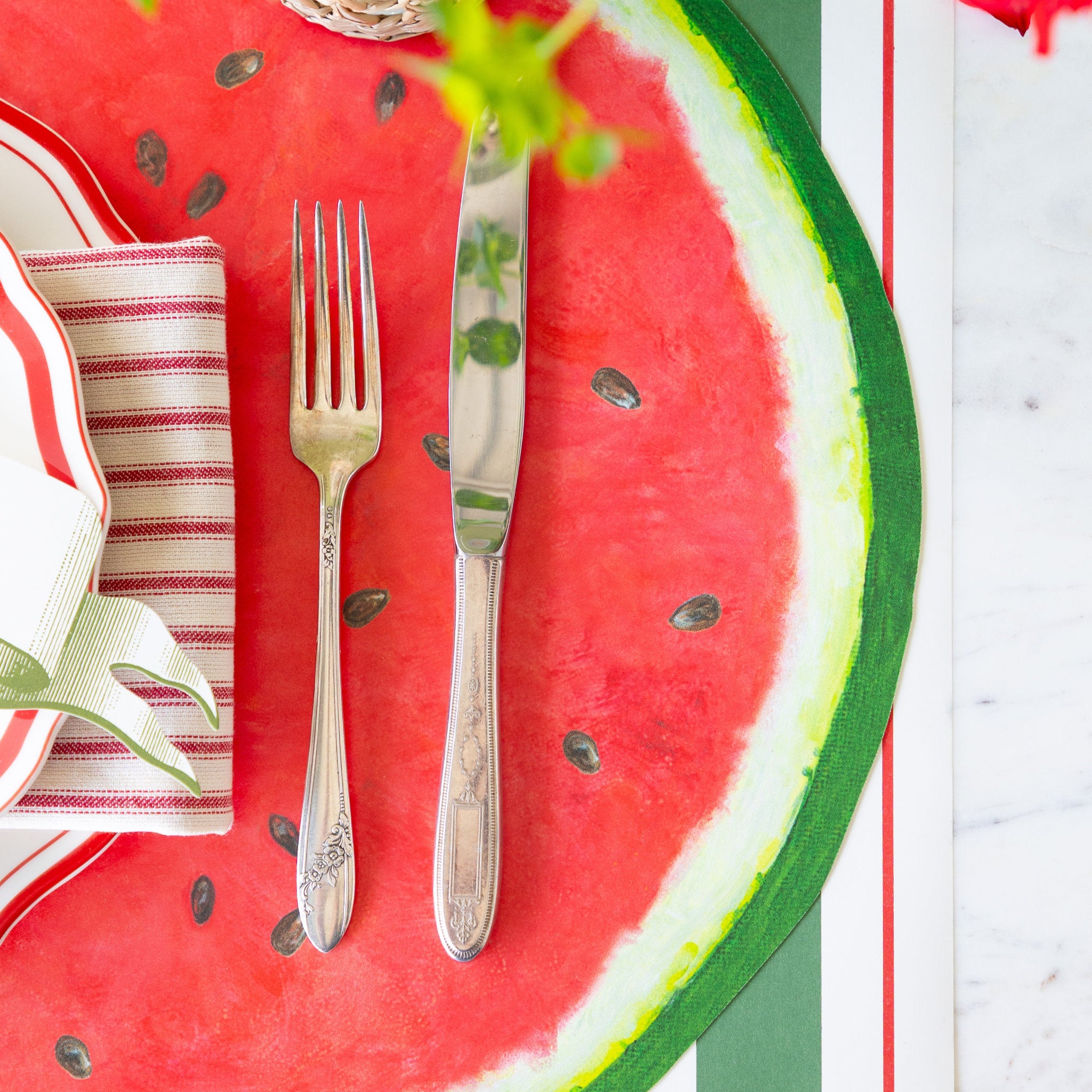 Table setting with Die-cut Watermelon Placemat, silverware, and striped napkin the Green & Red Awning Stripe Runner.