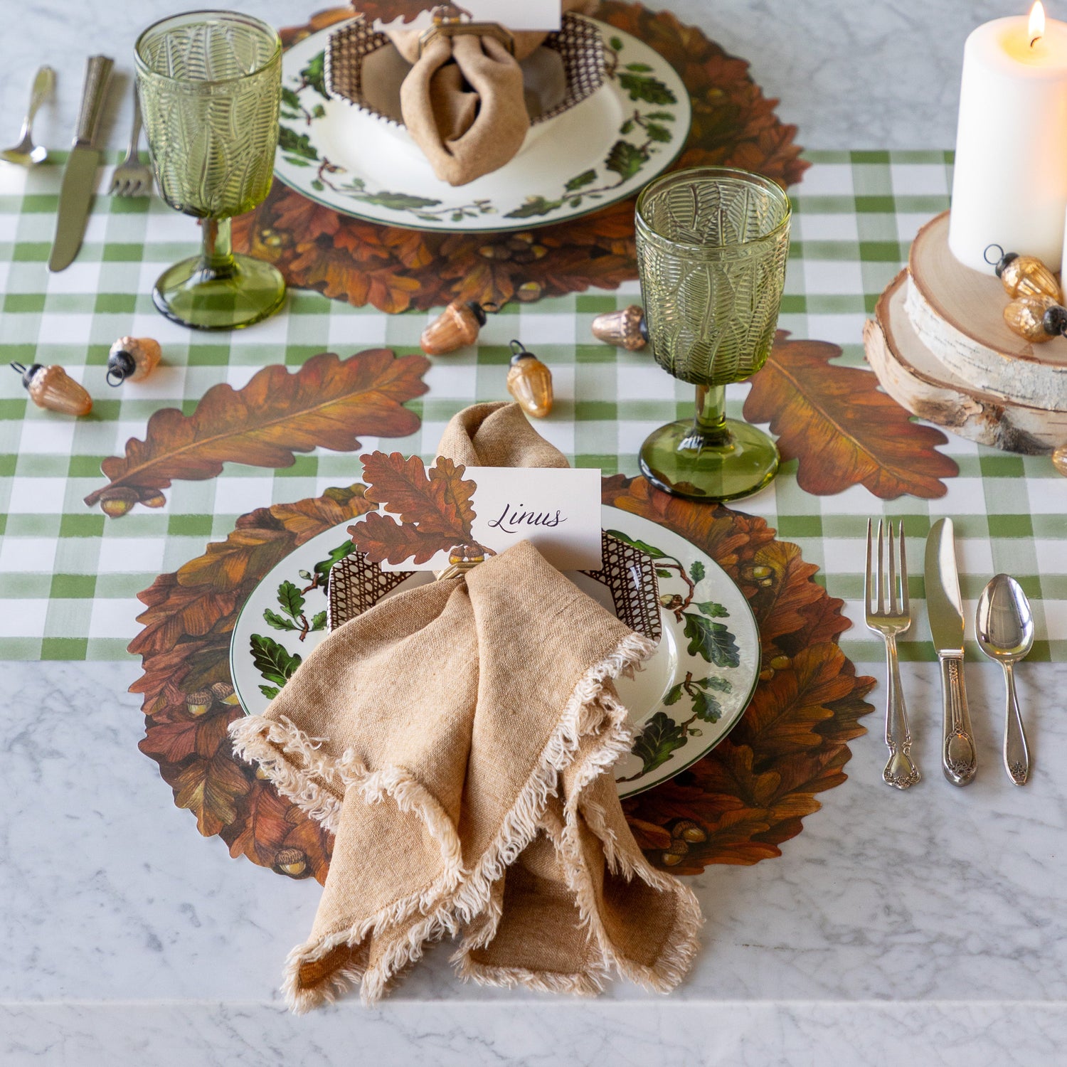 Thanksgiving table setting with Die-cut Autumn Wreath Placemats, Autumn Leaf Table Accents, candles, Glass Acorn Ornaments and Autumn Leaves Place Card on the Moss Painted Check Runner.