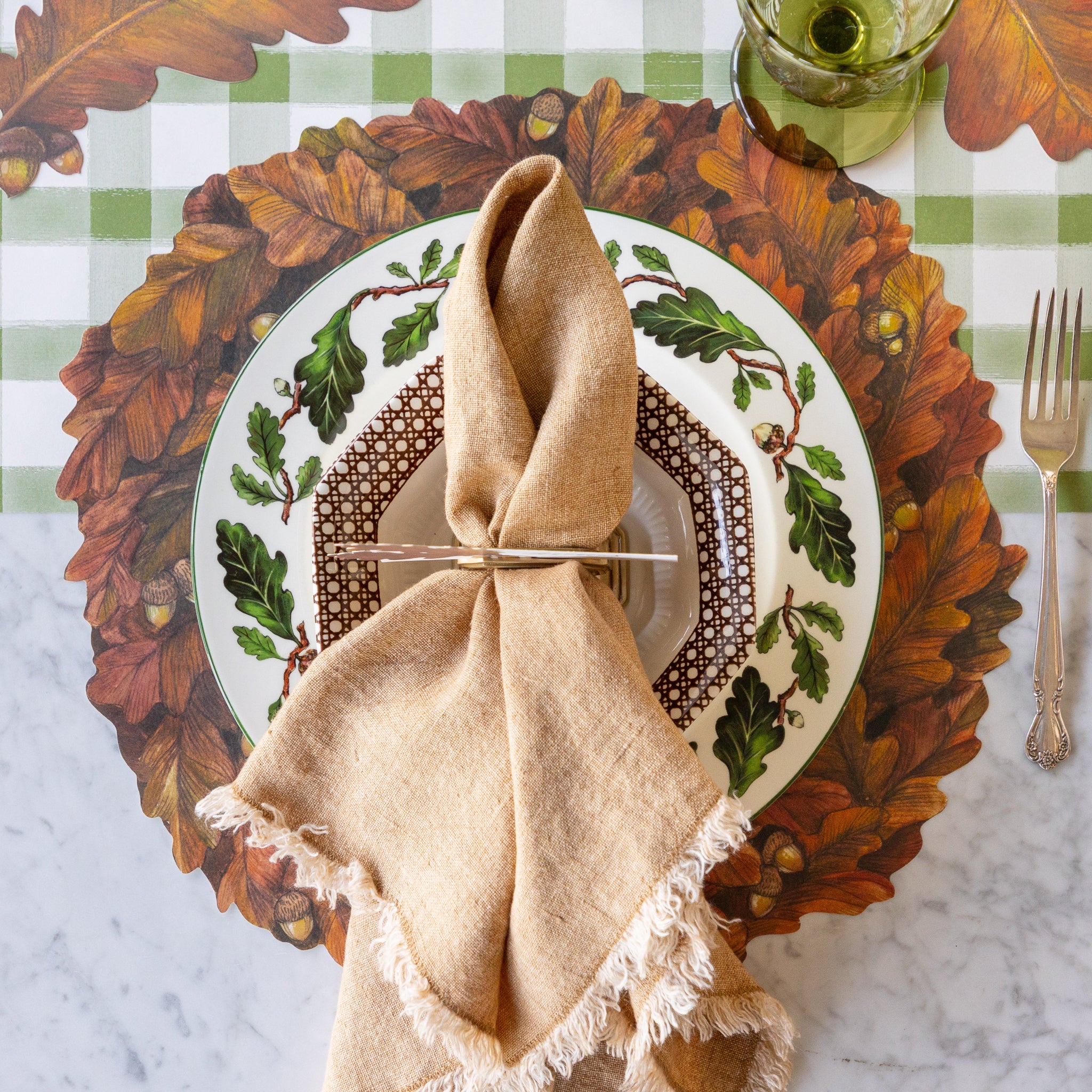 Thanksgiving table setting with the Die-cut Autumn Wreath Placemat, vintage leaf design plate and tan fringed napkin on the Moss Painted Check Runner.